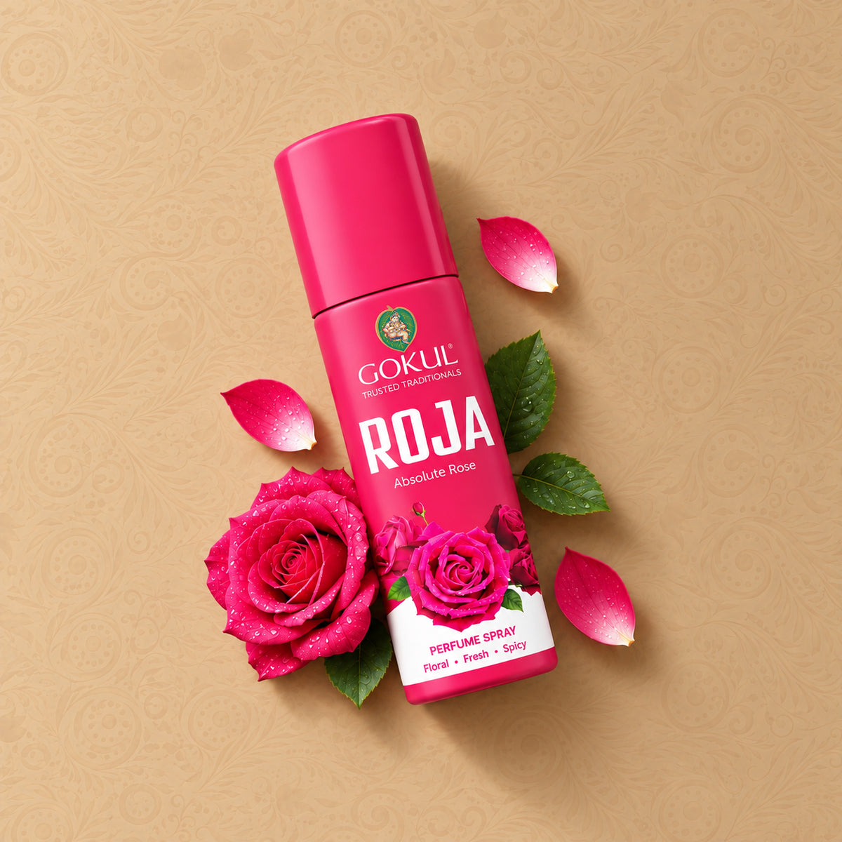 A bottle of Gokul Roja Absolute Rose perfume spray, styled with fresh pink roses, green leaves, and pink petals on a textured beige background.