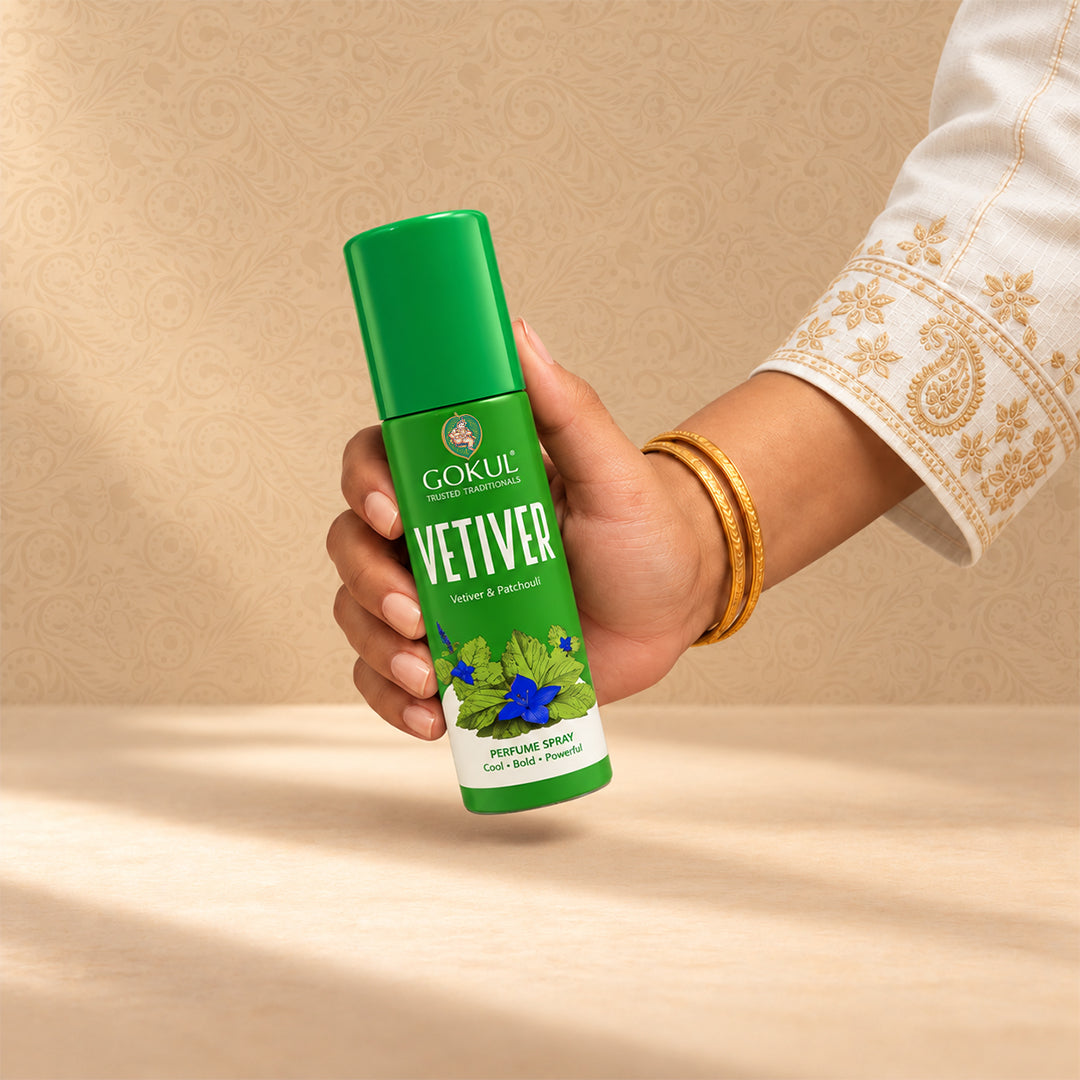 A hand holding a green bottle of Gokul Vetiver Vetore & Perfume Oil against a warm beige patterned background.